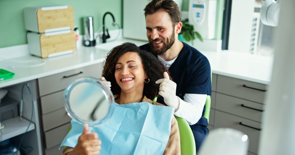 Clinic, happy and dentist with woman with mirror for consulting, teeth whitening and wellness. Healthcare, dentistry and man with patient smile for dental hygiene, oral cleaning and medical services