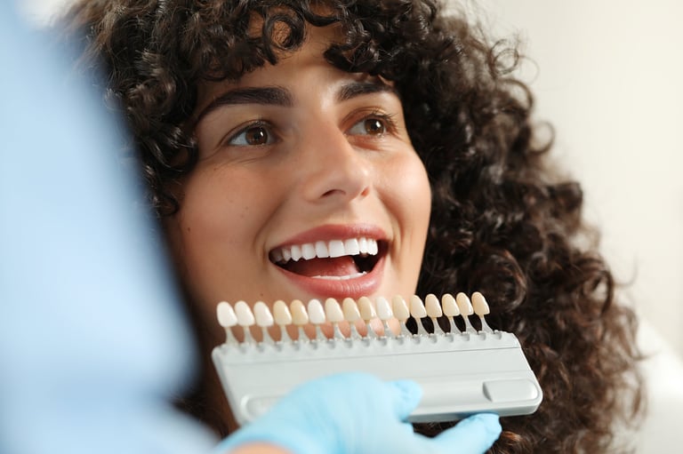 Doctor checking young woman's teeth color in clinic, dental veneers consultation