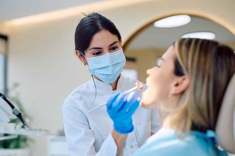 Female dentist wearing mask and gloves performing an oral examination on a woman in a modern dental clinic
