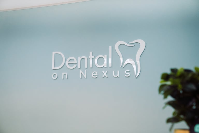 Dental on Nexus logo displayed on a light blue wall with a green plant visible in the corner