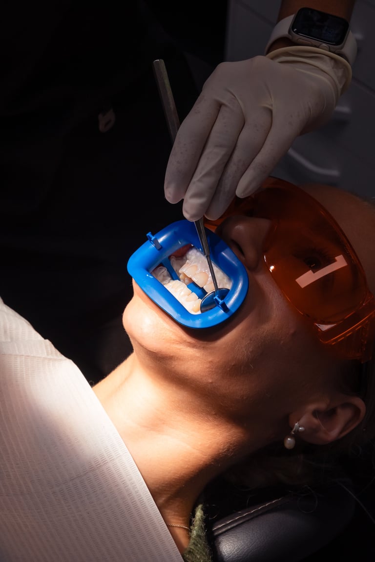 Gloved hand holding a blue mouth guard over a persons open mouth during dental examination