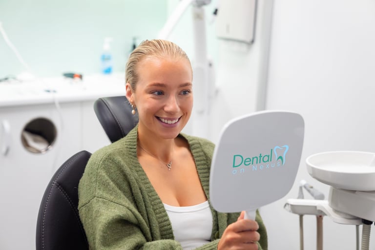 Happy woman smiling while holding a dental mirror in a modern dental office