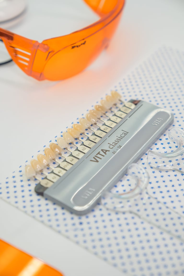 Shade guide of dental veneers or tooth color samples with orange safety glasses on blue dotted surface