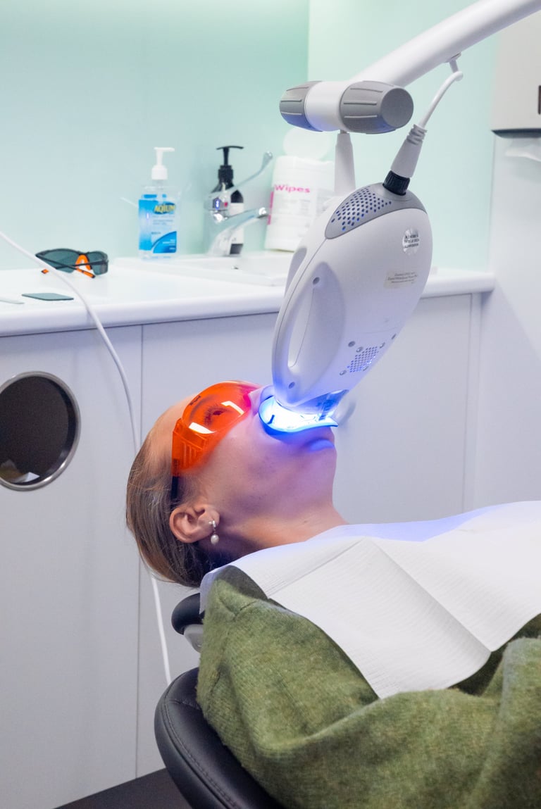 Patient receiving LED light therapy treatment on face using professional dental or dermatological device in a clinical setting